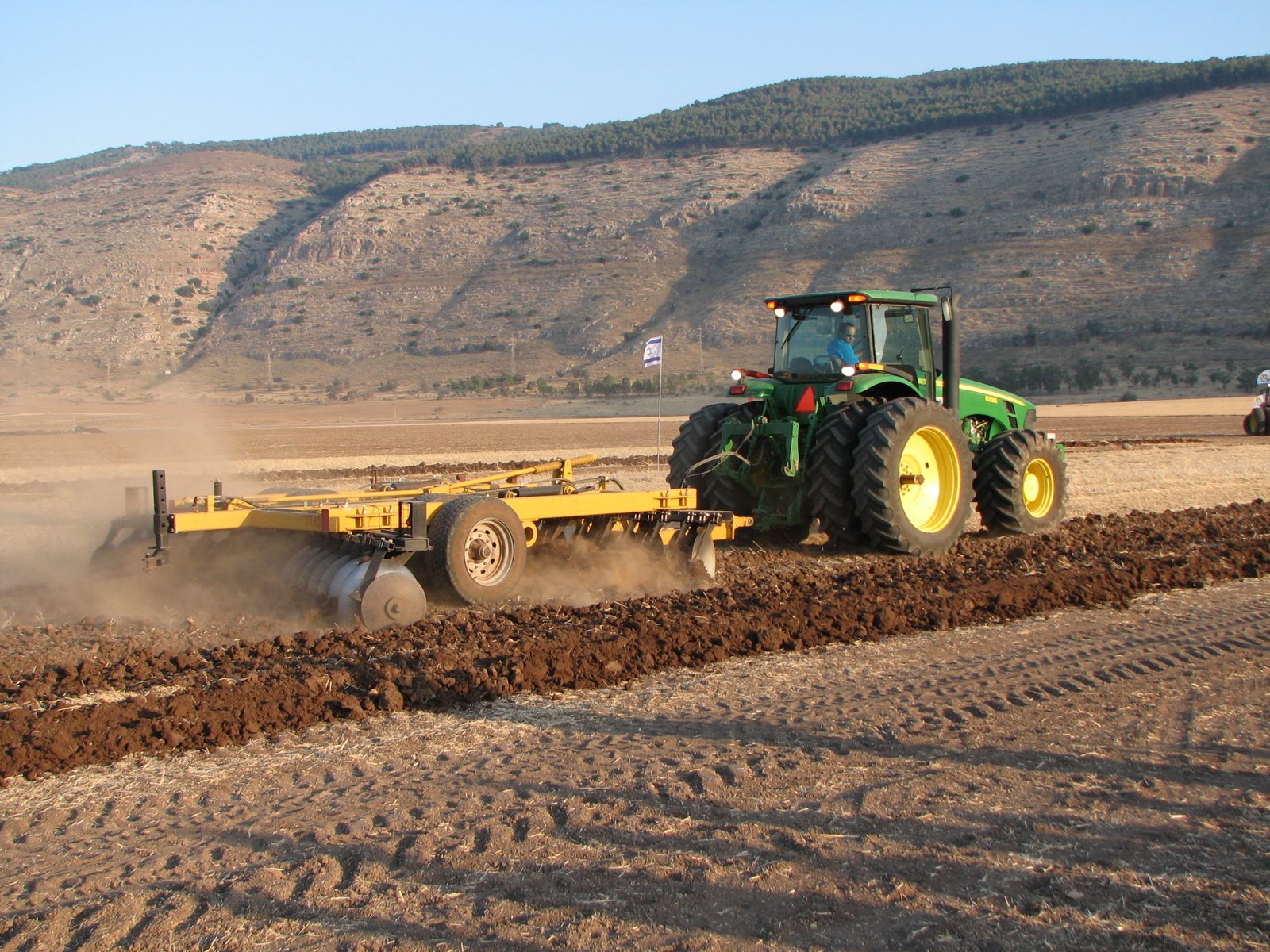 Tractor pulling a disc harrow across a ploughed field